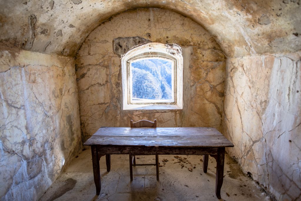 abandoned room of the first world war with old wooden table and chair with window on the rocks of the alps forte Corbin on the plateau of Asiago Veneto Italy