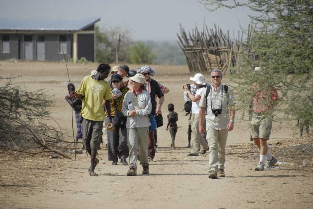 Kolcho, Ethiopia – March 17th, 2012: Unidentified Western tourists are welcomed by Karo people in Kolcho, Ethiopia. Income from tourists becomes substantial for locals, but it destroys their traditional life.