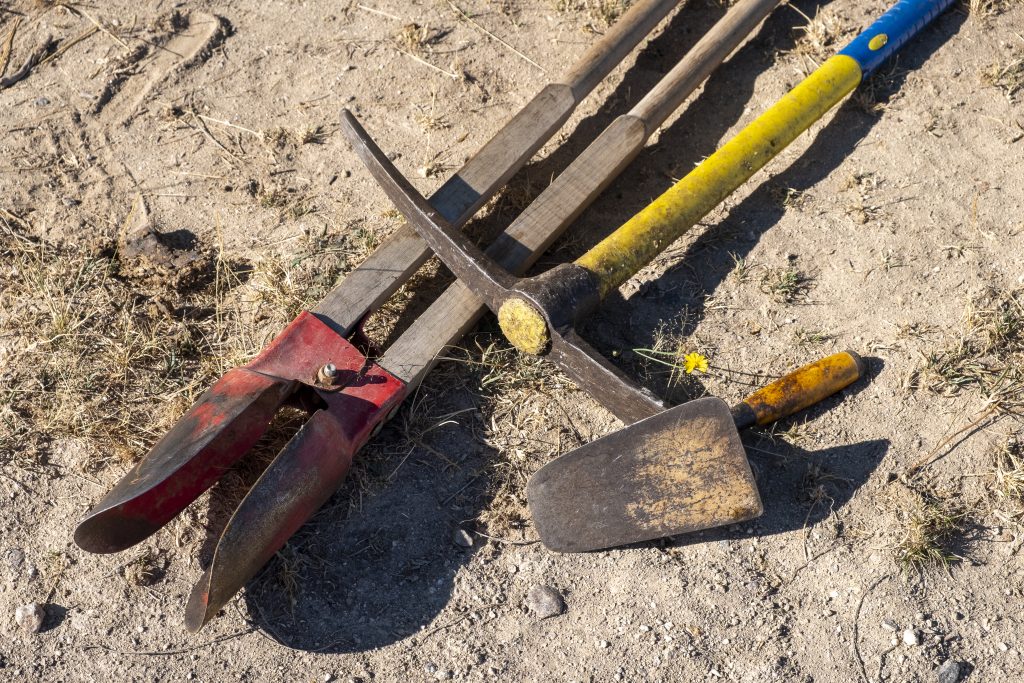 tools in an archaeological excavation: shovel, pick, pickaxe, trowel and digging pits